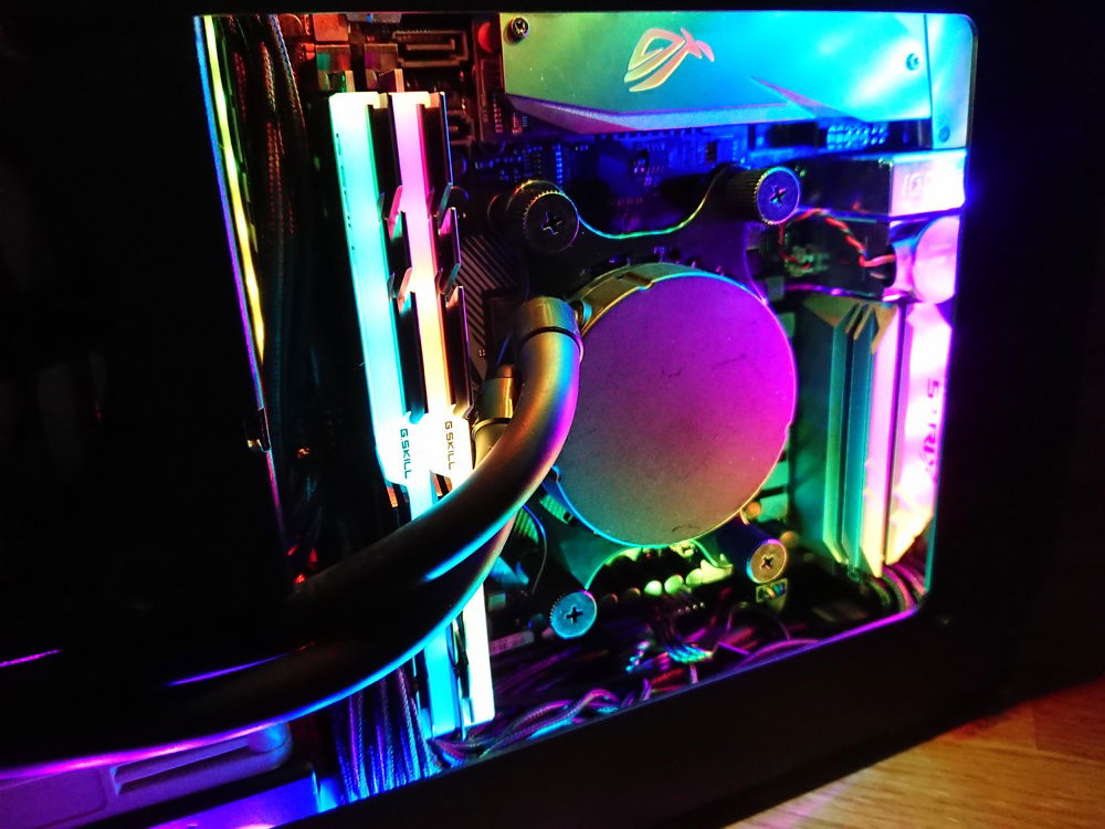 Now we are having a closer look at the RGB side of the build, where the Asus Strix X370-I Gaming Motherboard is installed, with a Ryzen 2700X under the Asetek LC545s Water Block. For the RAM there was pretty much just one choice: Trident Z RGB 16 GB Modules, which feature Adressable RGB LEDs, with a reasonable clock rate, in this case 3600 MHz Modules, which are running at 3333 MHz, featuring a Samsung B-Die. For Storage I sticked with a 1 TB EVO 960 NVMe SSD from Samsung, which is installed below the Heatsink at the top of the motherboard.