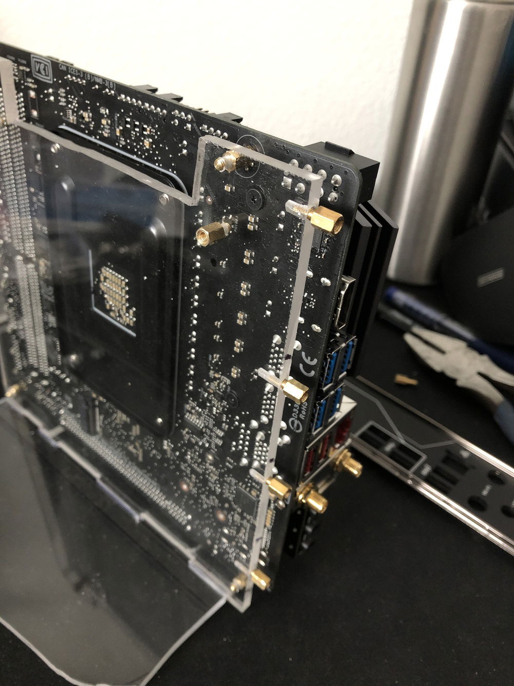 The custom back face with all the I/O ports screw into these motherboard standoffs in the acrylic frame.