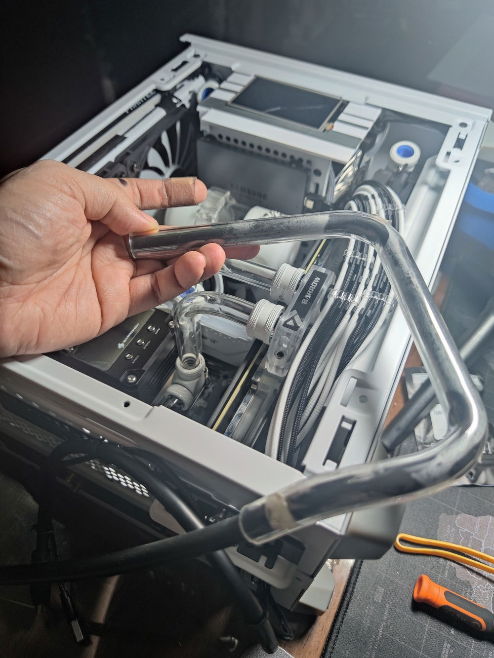 This tube connects the top radiator to the bottom one, bypassing the PSU cage due to necessity. It consists of two complex bends top and bottom to clear the side panel. 

It turned into a kind of centerpiece and frame for the internal LCD, I'm happy how it turned out.