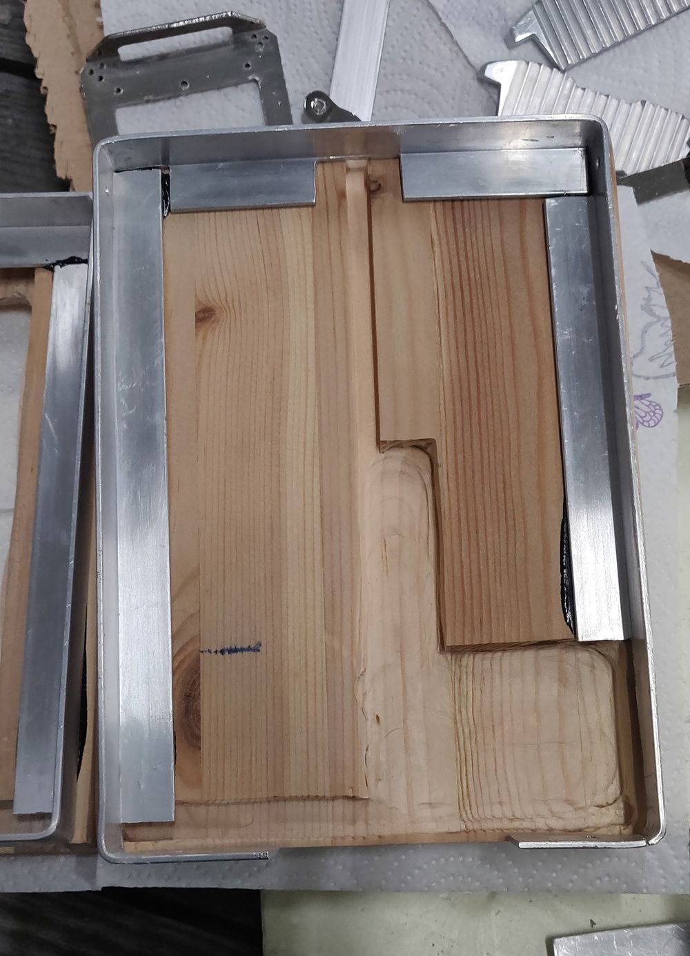 Bent some L-profile aluminium to shape of a frame, glued with strong adhesive (made a test piece with around the same contact area and managed to bend the 2mm aluminium slightly and get a crack in the wood before it gave up so its probably enough, may add some screws later down the line if it doesn't hold, didn't bother to get everything sanded even and brazing the gaps in the aluminium as the inside is going to be covered with some rubber paint just in case and to dampen vibrations from the main frame to case.