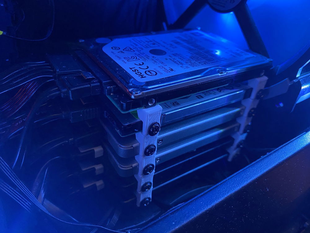 The 4 ssd's and the 2 2.5 inch hdd's stacked with 3d printed brackets resting on the cables underneath.