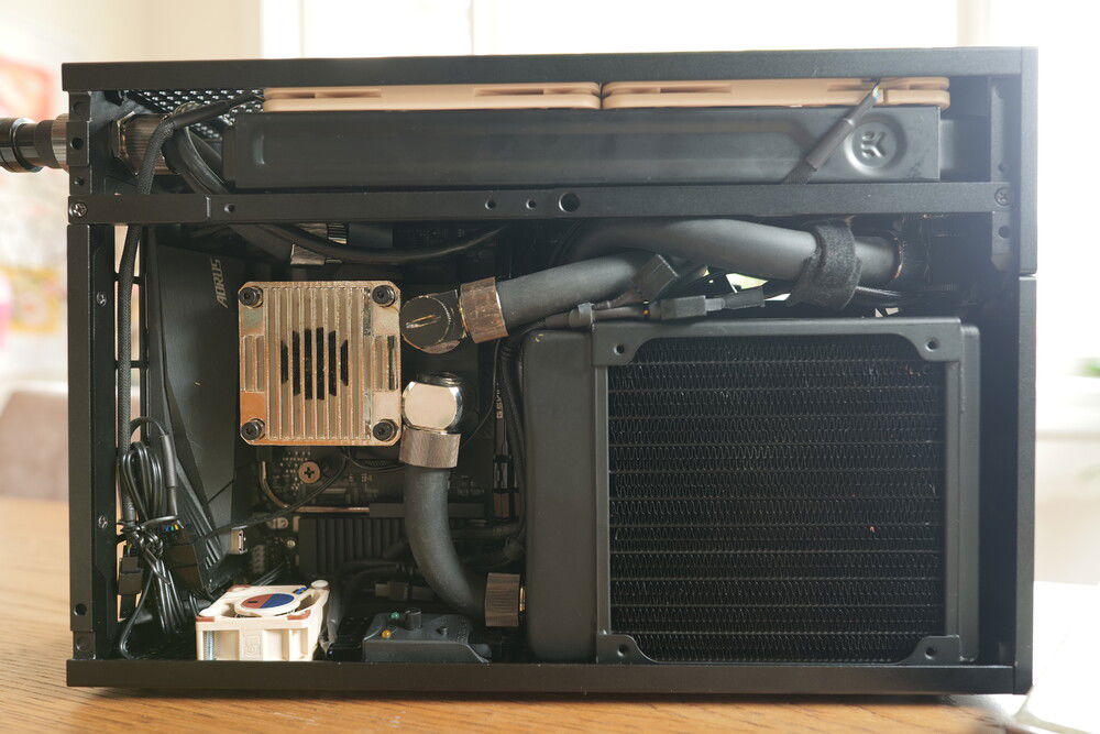 The new 120 xspc slim radiator hides a 25mm arctic fan - exhaust. A handy pump-fill line is jammed from the pump top to what was previously the power-button. A 20x40mm Noctua fan keeps air flowing over the ddc pump housing.