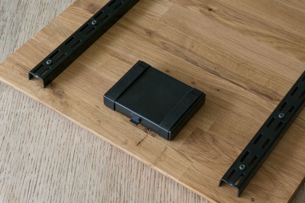 On the bottom side of the lid are two metal bars and a small toolbox. The metal bars keep the wooden lid from warping and keep it from sliding when closed. The toolbox is held securely in place by hook-and-loop (velcro) fasteners. It contains a tiny screwdriver, spare screws and fittings, a Windows recovery USB-stick (it has saved me more than once) and can also hold the rubber feet, when they are not in use.