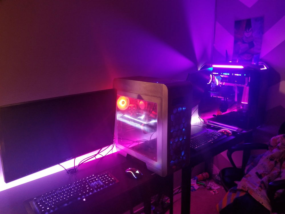 his and hers gaming desktops both running with desktop lights on and room lights off.